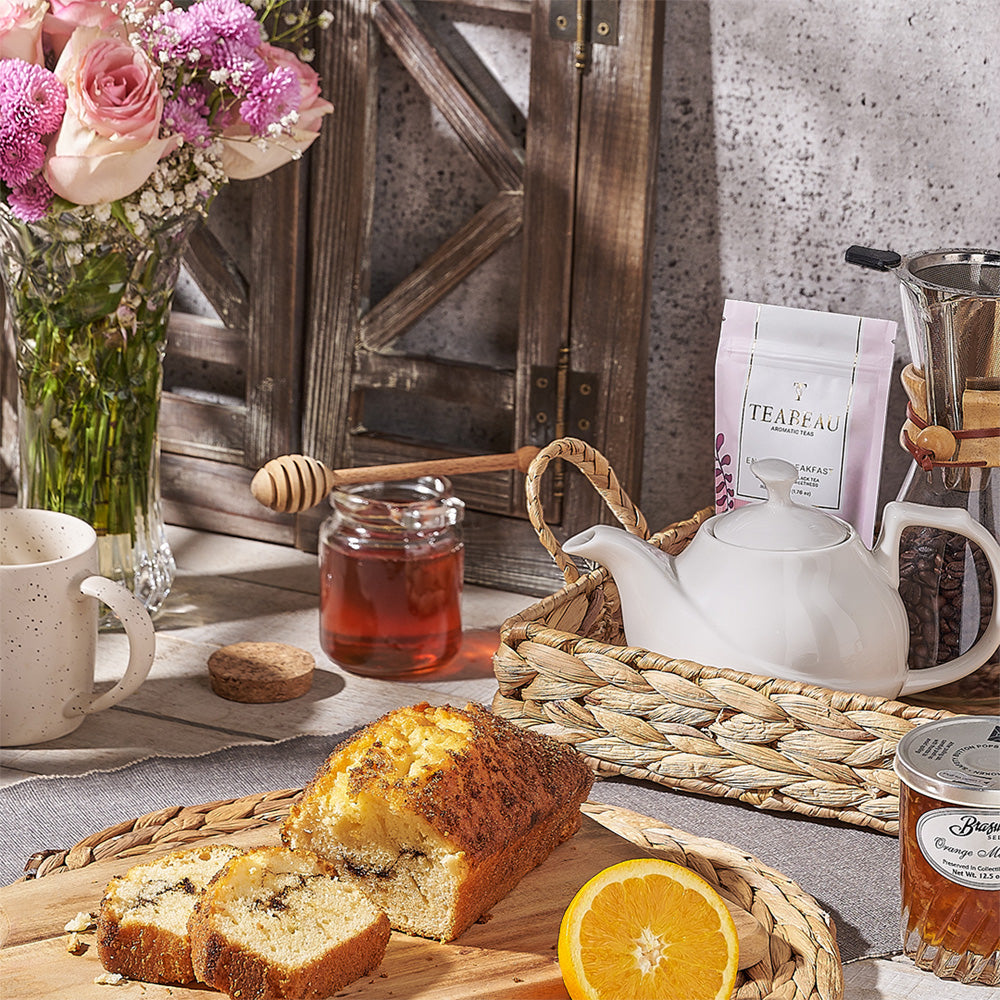 Tea setup with bread, honey, and flowers on a rustic wooden table.