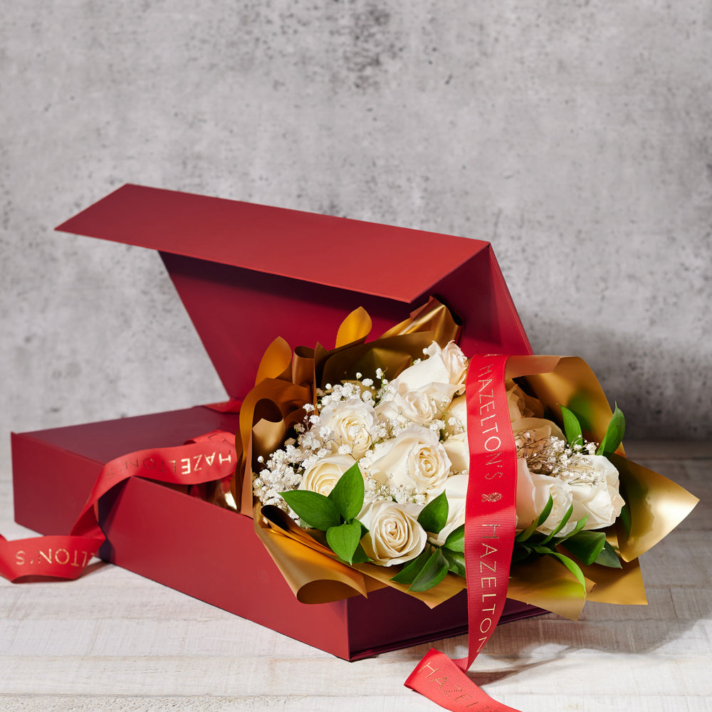 Bouquet of white flowers in a red box with gold wrapping and a red ribbon on a gray background.