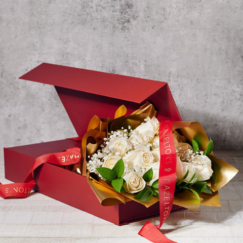 Bouquet of white flowers in a red box with gold wrapping and a red ribbon on a gray background.